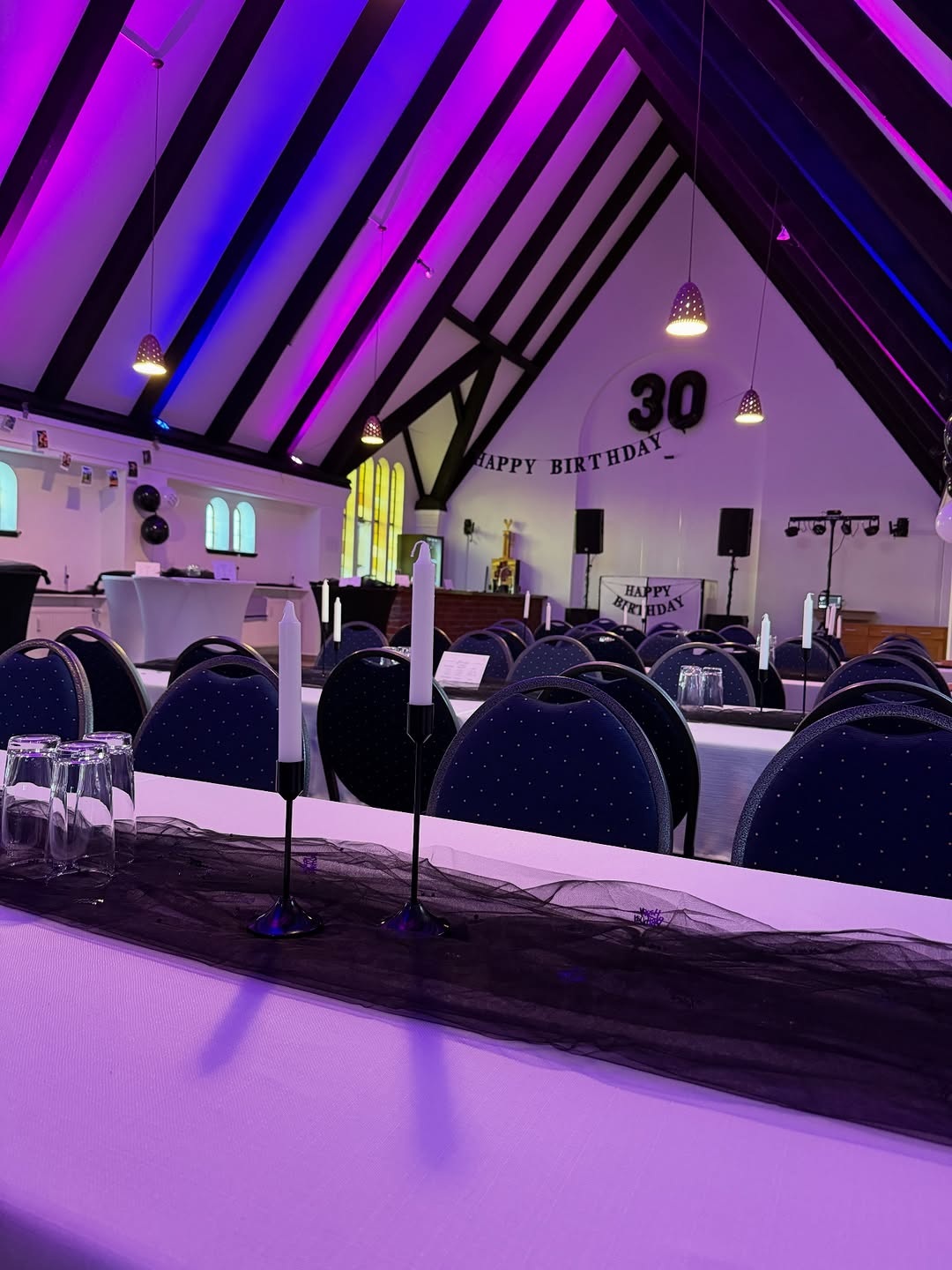 Festlich eingedeckte Tafelreihen mit heller Bestuhlung im Saal